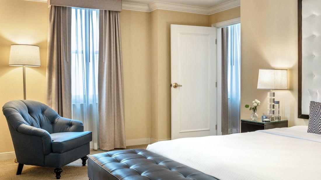 Bed with side table and couch near doorway and window in Specialty Suite at Warwick Allerton Chicago
