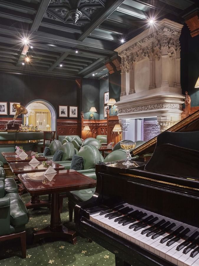 Duke's Bar lounge, featuring green armchairs placed by a piano at Hotel Westminster Paris