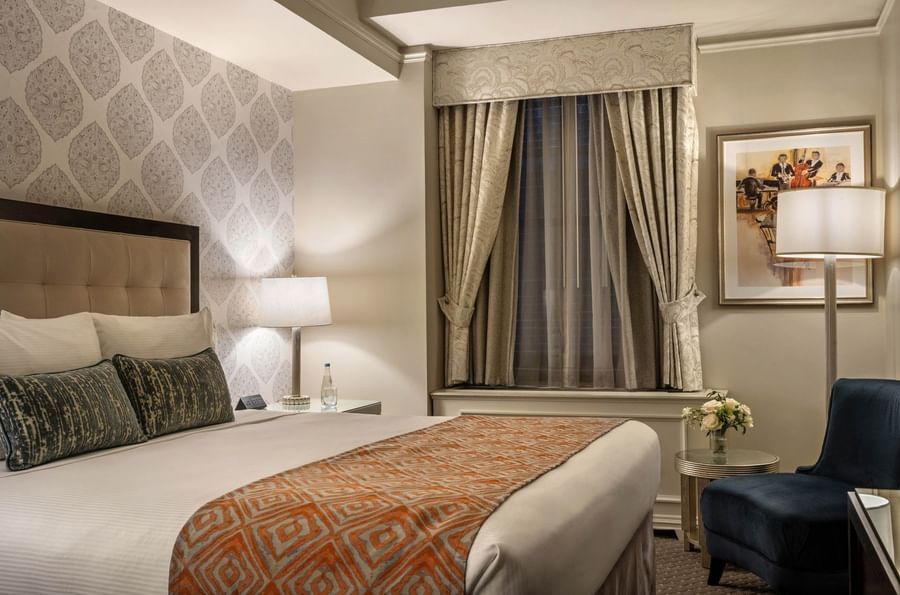 Elegant hotel room with a large bed, patterned bedspread, and modern decor at Warwick New York.