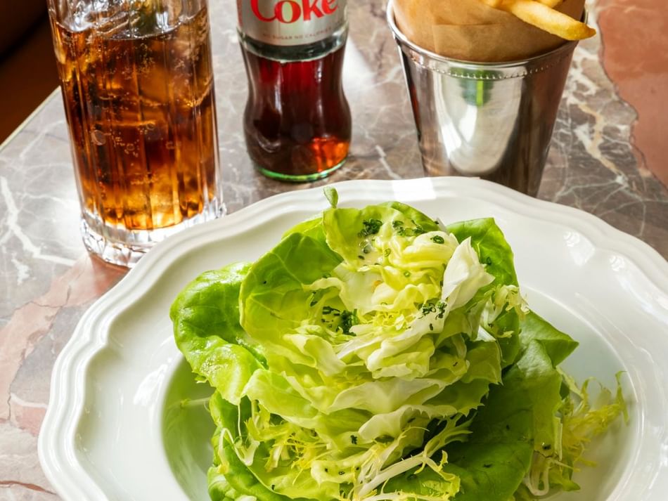 Close-up of fresh green salad with lettuce, French fries, and a glass of cola at Bar Remi in Granduca Houston