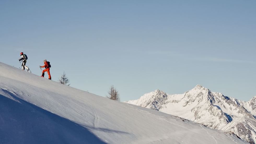 Couple on a hike in snowy mountains near Falkensteiner Hotel Kronplatz