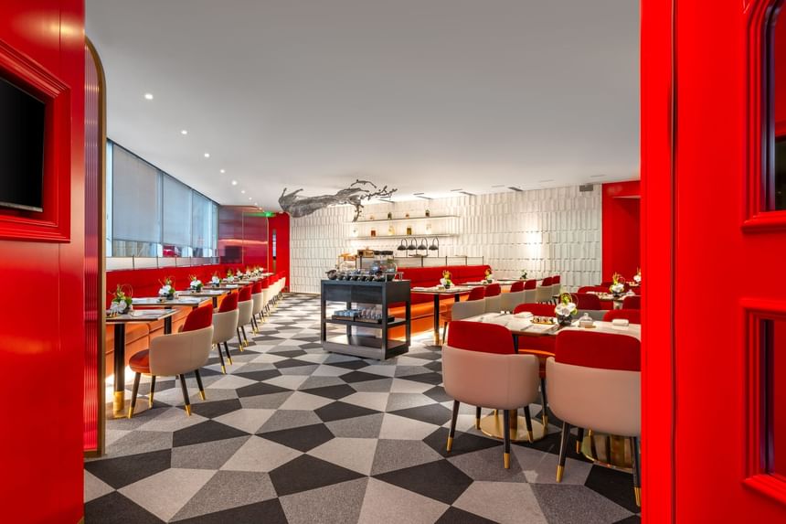 Spacious dining area at George's Restaurant in Hotel Éclat Beijing, featuring red accents and geometric flooring.