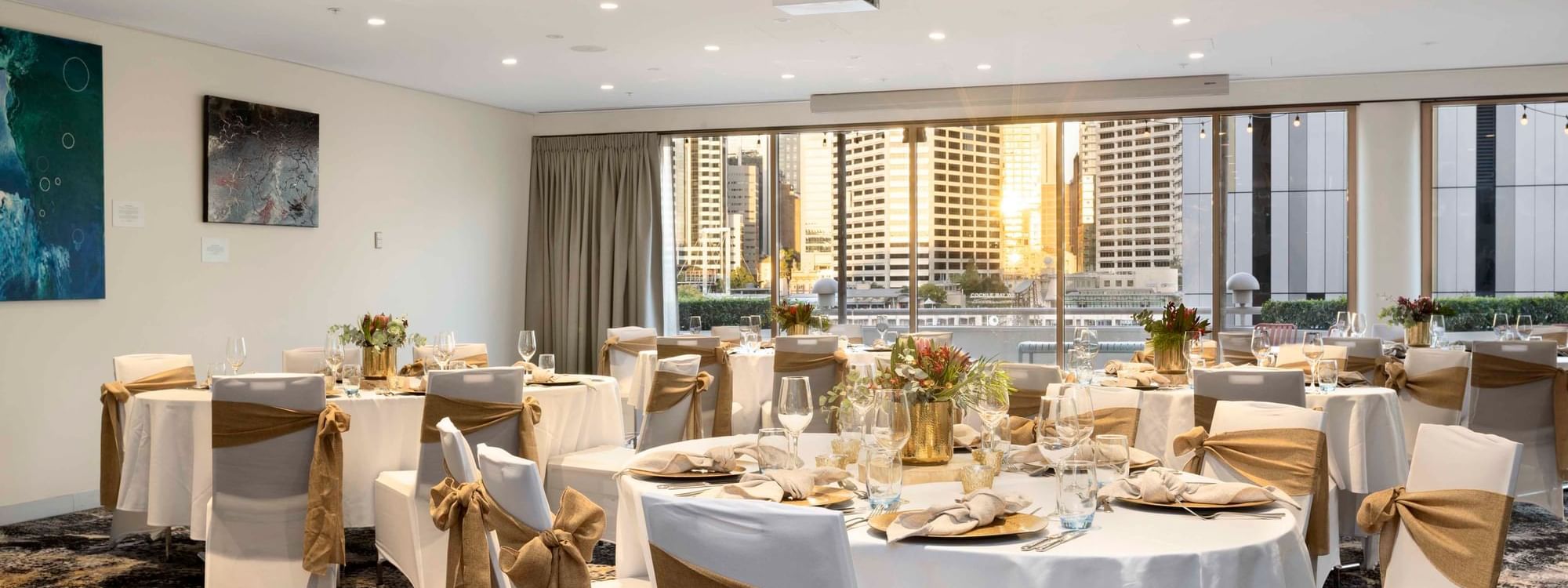 Set up banquets by the large windows with city views in The Barossa Room at Novotel Sydney on Darling Harbour