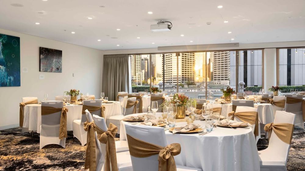 Set up banquets by the large windows with city views in The Barossa Room at Novotel Sydney on Darling Harbour