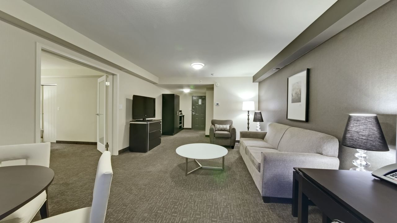 Living area of guest room with couches, tv and table