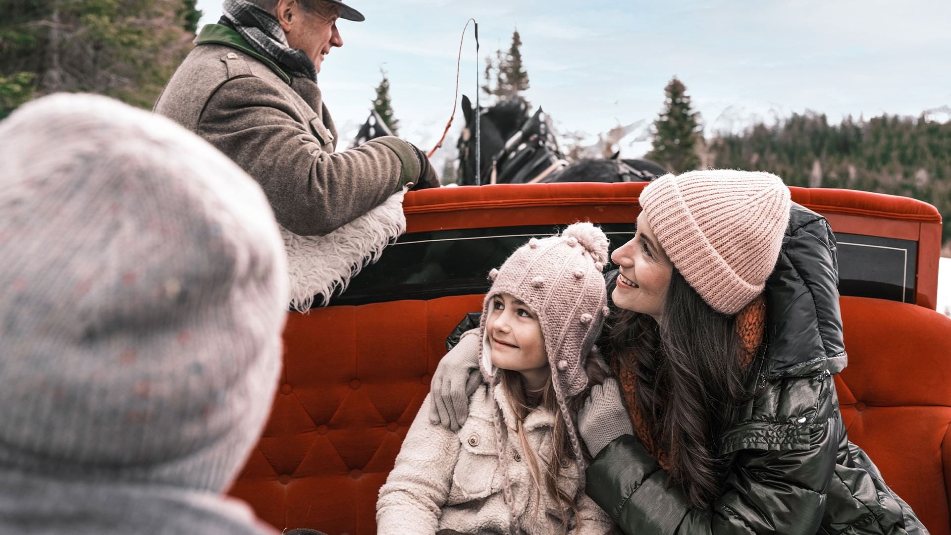 Familie genießt eine Pferdekutschenfahrt durch eine winterliche Landschaft mit Schnee und Bäumen.