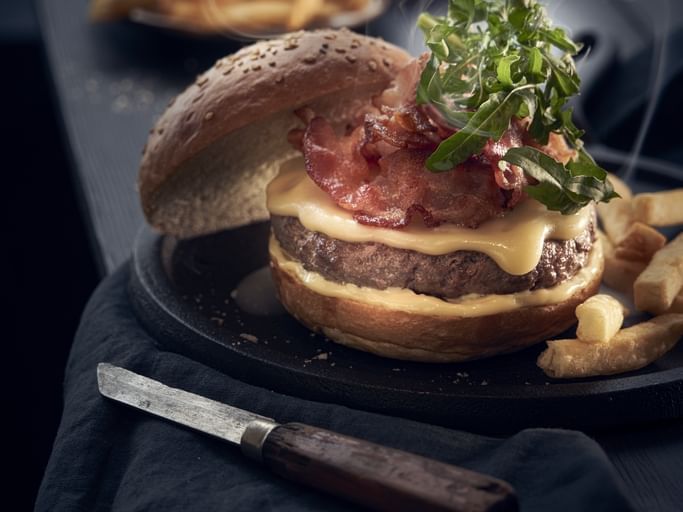 Close-up of a served cheese hamburger with fries, One Hotels