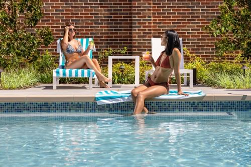 Girls chatting near an outdoor pool at Warwick Melrose Dallas