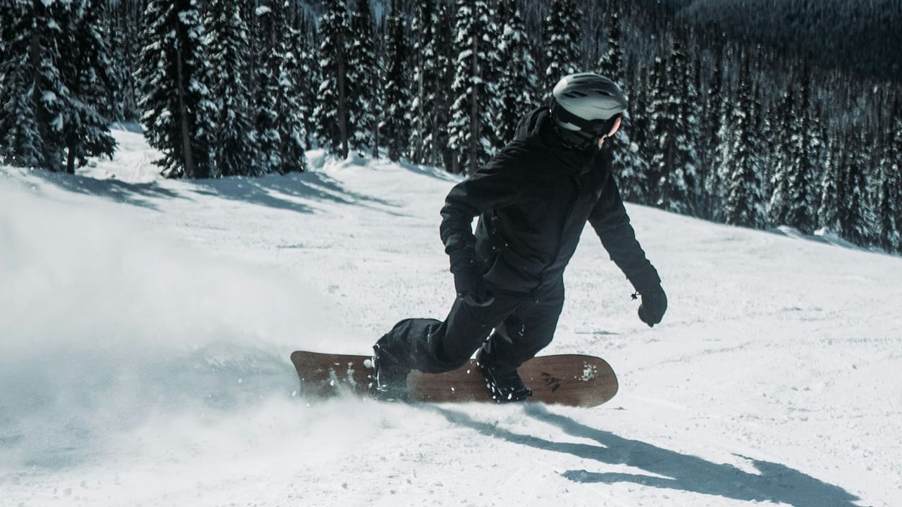 Snowboarder carving through fresh powder on a snowy mountain