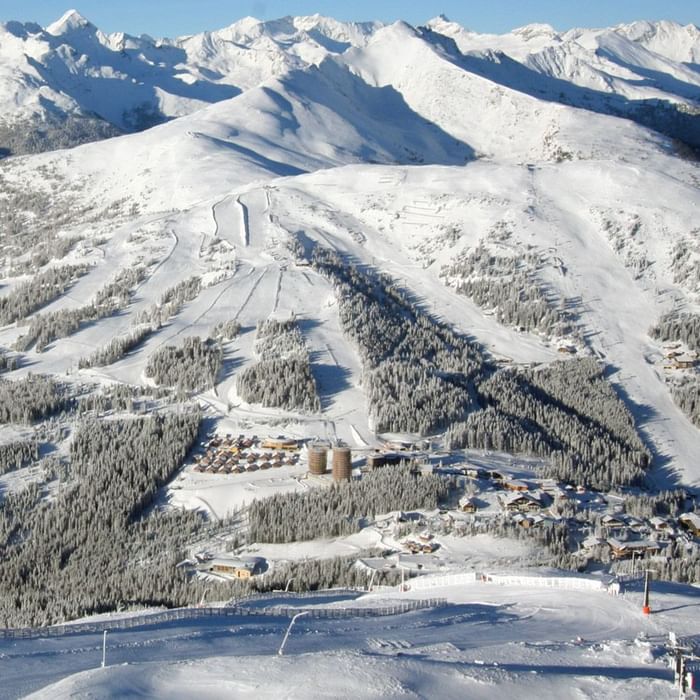 Aerial view of snow-covered Falkensteiner Residences Edelweiss with a snowy mountain backdrop