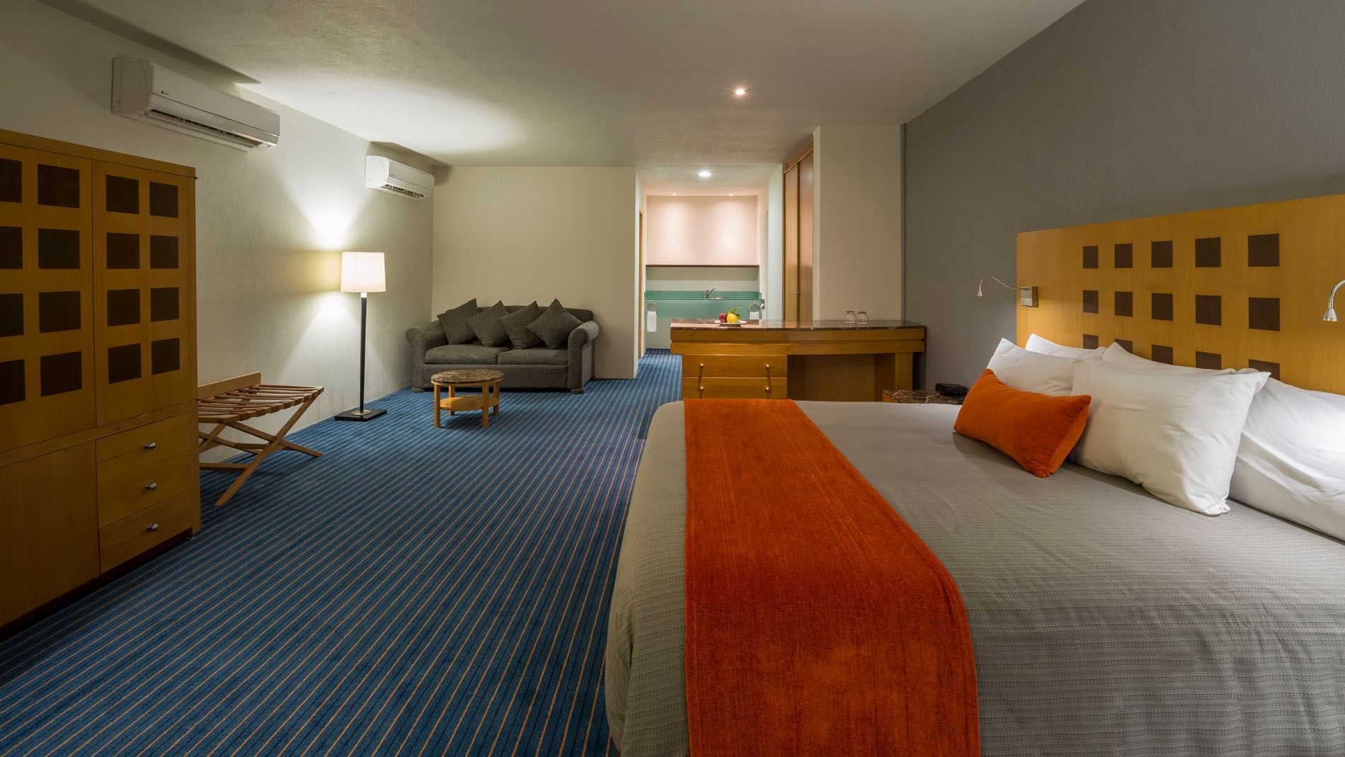 King Junior Suite at Real Inn Nuevo Laredo featuring a sofa, marble island, and a bed with an orange throw