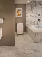 White marble bathroom featuring a soaking tub by a vanity under bright lights in Magnolia Suite at Warwick Seattle