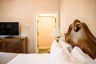 Nightstand & TV by the cozy bed in European Room at The Exeter Inn