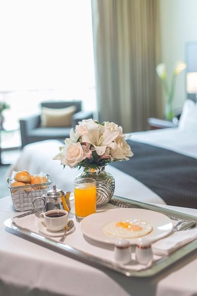 Breakfast tray with eggs, coffee, juice, & a vase of flowers served by bed in Superior Room at Hotel Los Delfines & Casino