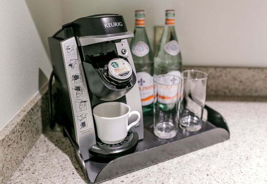 Keurig coffee maker with mug near two water bottles in King Suite Lakeside at Clemson University Conference Center & Inn