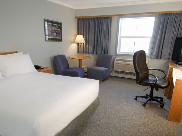 queen bed with two chairs and a work station