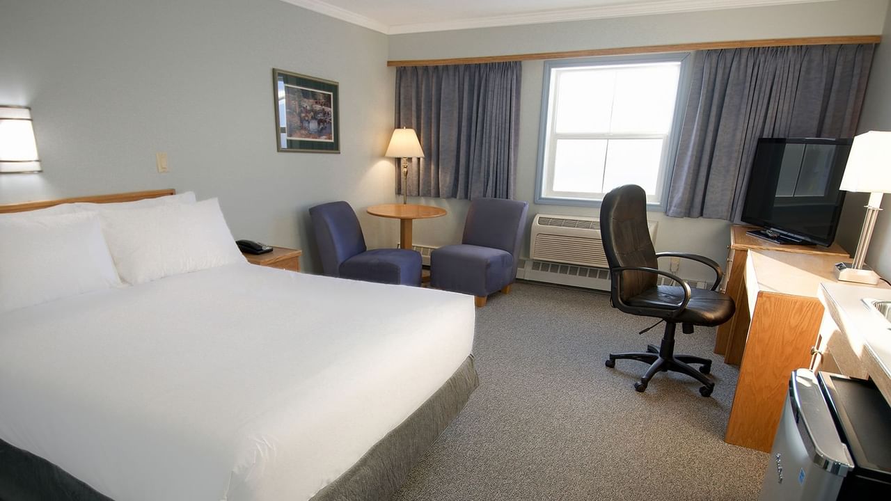 queen bed with two chairs and a work station