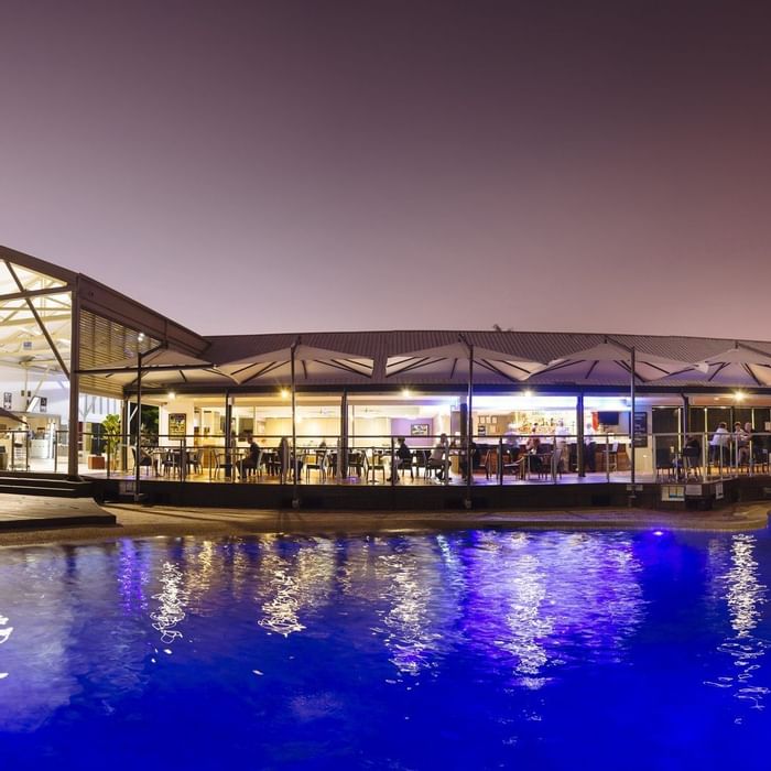 Celsius Restaurant & Bar by a glowing pool illuminated under a night sky at Mercure Hotel Townsville