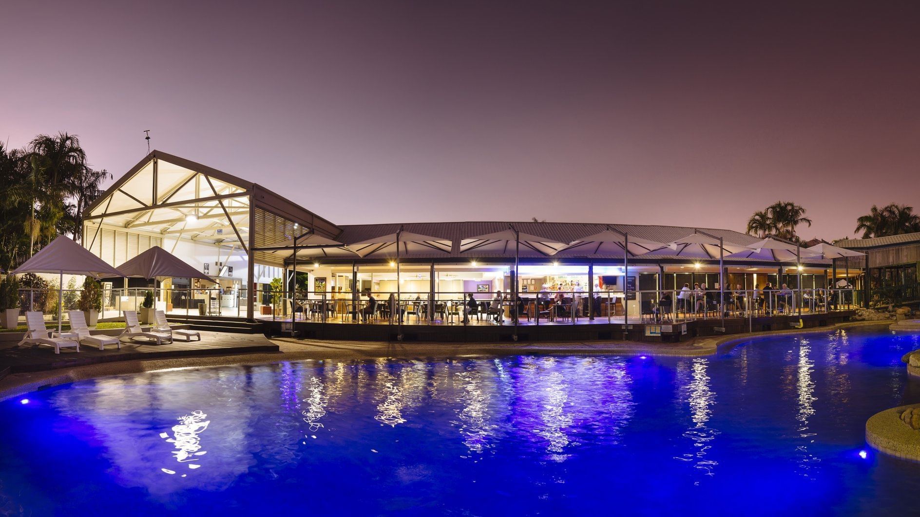 Celsius Restaurant & Bar by a glowing pool illuminated under a night sky at Mercure Hotel Townsville