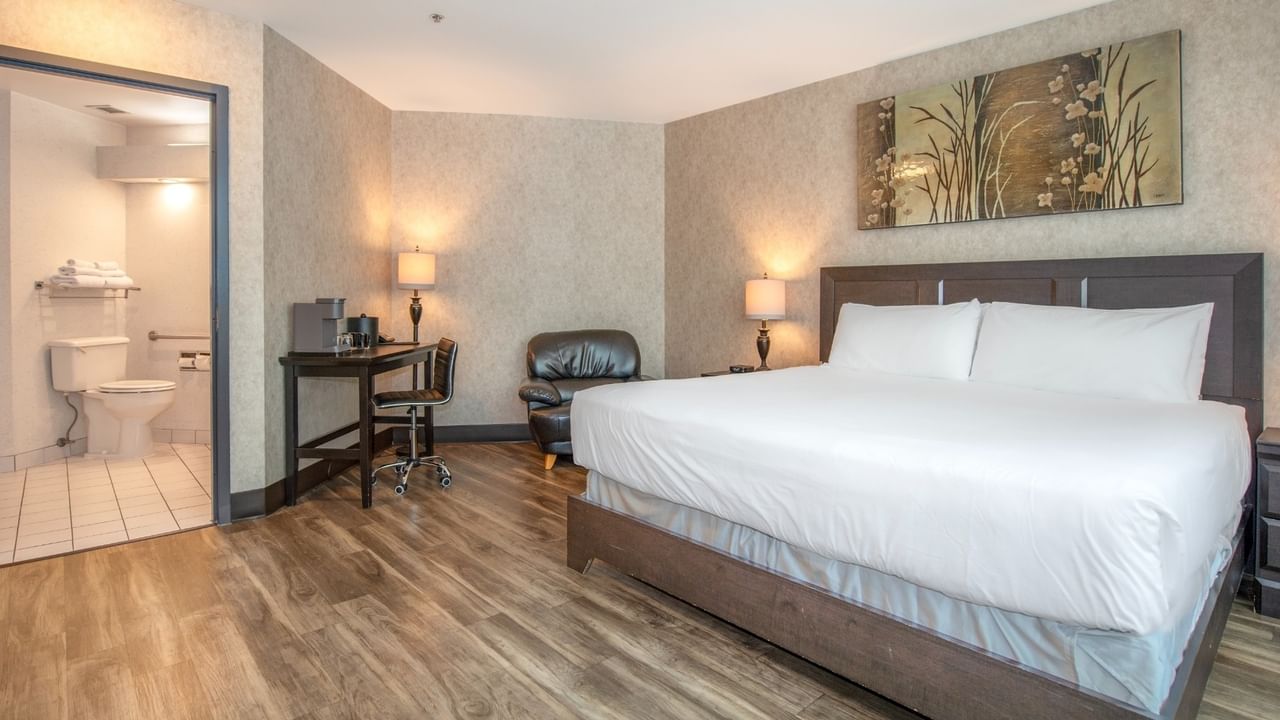 Coast Accessible King with a large bed, wooden floors, desk, chair, and a bathroom at Coast Lonsdale Quay Hotel