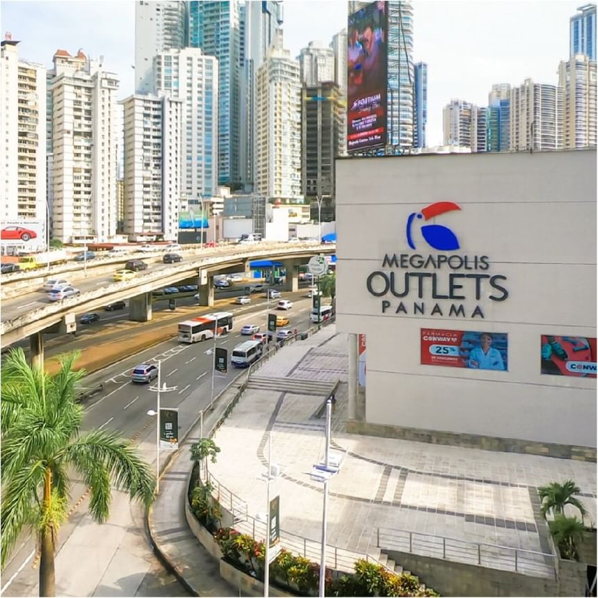 Exterior de un centro comercial junto a una carretera transitada y rascacielos cerca de Megapolis Hotel Panama