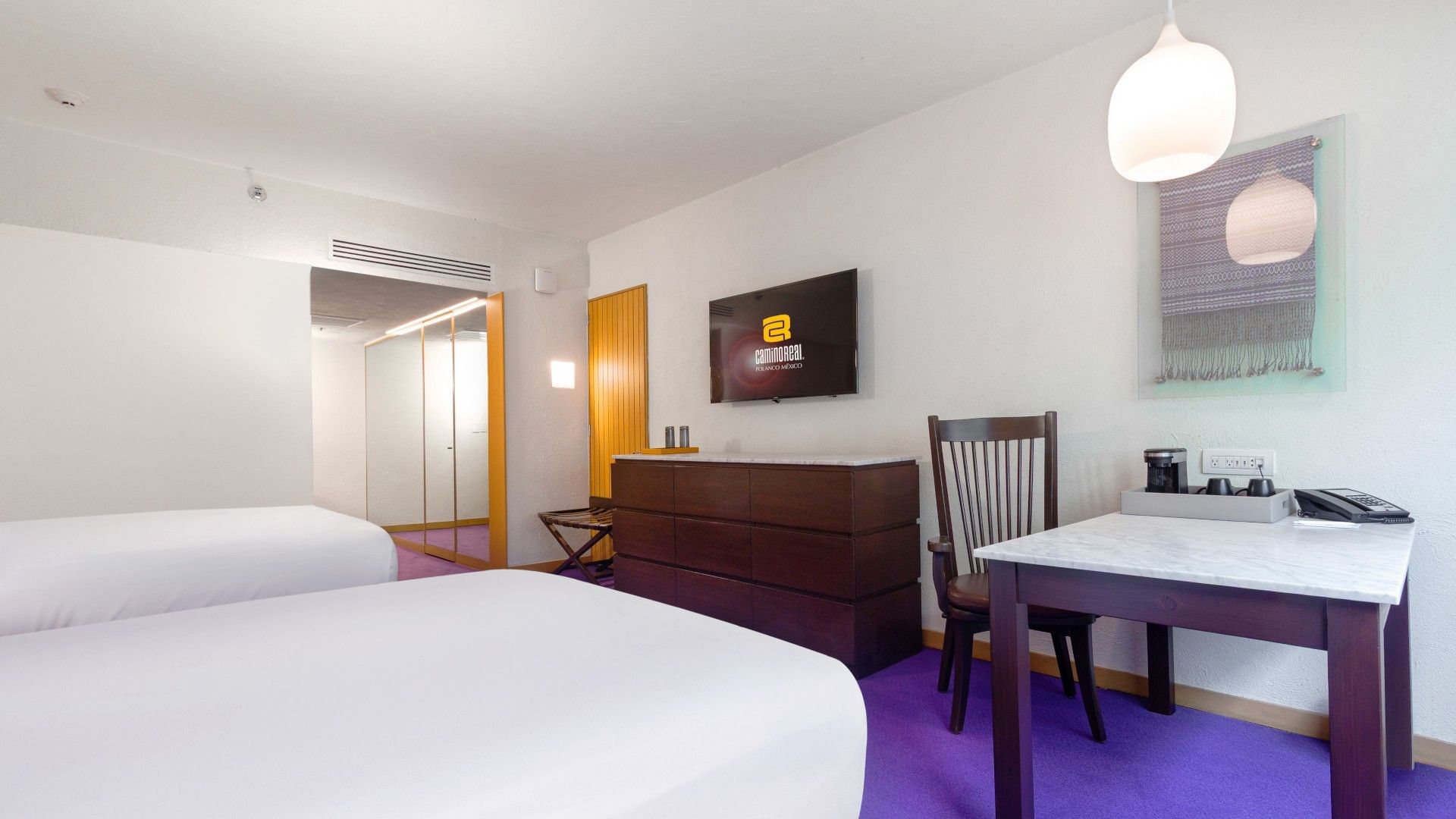 2 Double Superior Deluxe room featuring a dark wood dresser, white walls, and purple rug at Camino Real Polanco Mexico