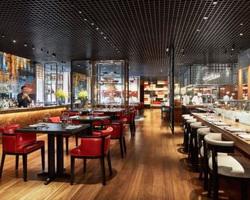 Square One interior with wooden floors, red chairs, and a bar area showcasing a variety of drinks at Park Hyatt Saigon