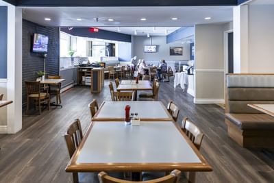 Spacious dining area with tables, booths, and wooden flooring in Gales Restaurant in Yarmouth at Rodd Grand Yarmouth