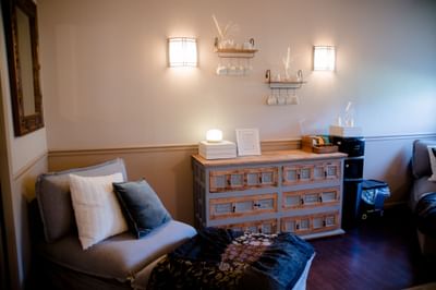 Chaise lounge chair beside a wooden storage cabinet and tea station in August Moon Spa at La Tourelle Hotel and Spa
