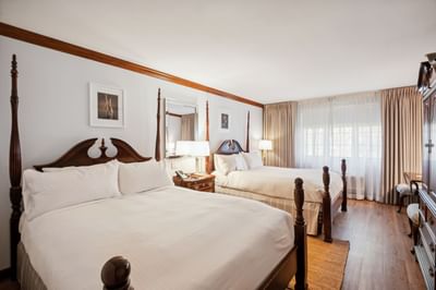 Two beds with white linens beside a table lamp near a large window in Traditional Two Queens at Avon Old Farms Hotel