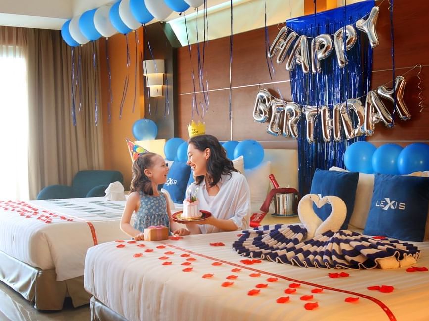 Mother and child celebrating birthday in a decorated hotel room