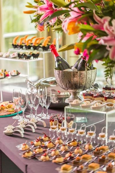 Lavish dessert buffet featuring champagne, assorted pastries, and elegant floral arrangements at Hotel Los Delfines & Casino