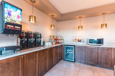 A well-stocked breakfast bar featuring dark wood cabinets and a selection of drinks and pastries at Carmel Bay View Inn