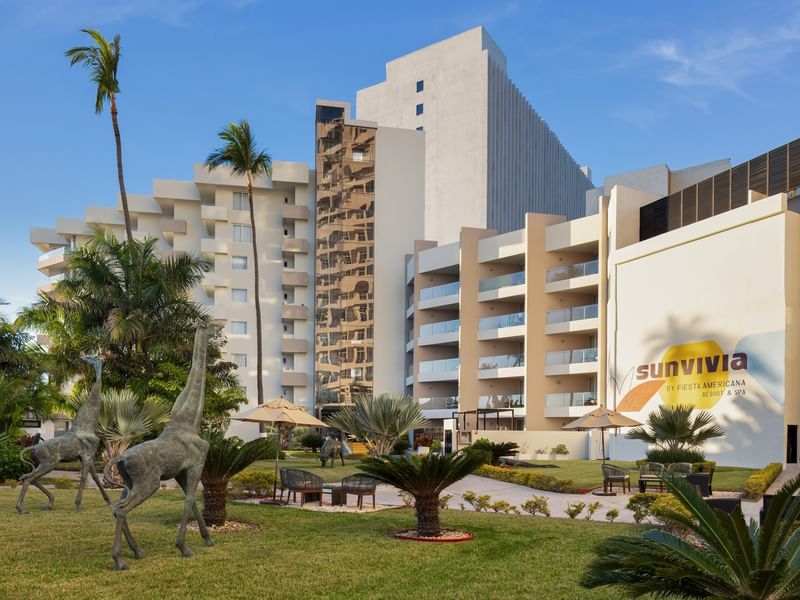 Lush resort garden at Sunvivia by Fiesta Americana featuring giraffe sculptures and modern hotel architecture