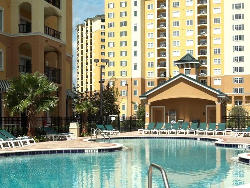 A resort pool with lounge chairs and a building in the background