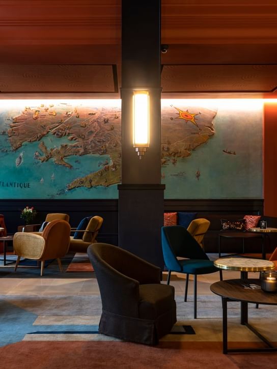 Stylish lounge with colorful seating and an artistic map wall, lit by modern lighting at Oceania Hotels