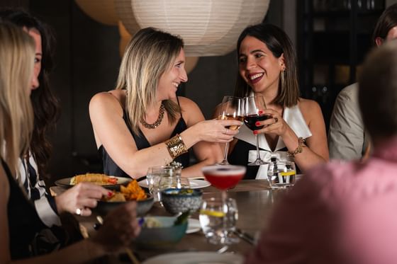 Two women toast with wine glasses at a beautifully set dining table in The Kitchens