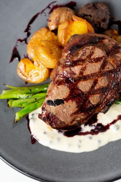 Close-up of steak with golden potatoes and fresh asparagus served at Stein Eriksen Residences