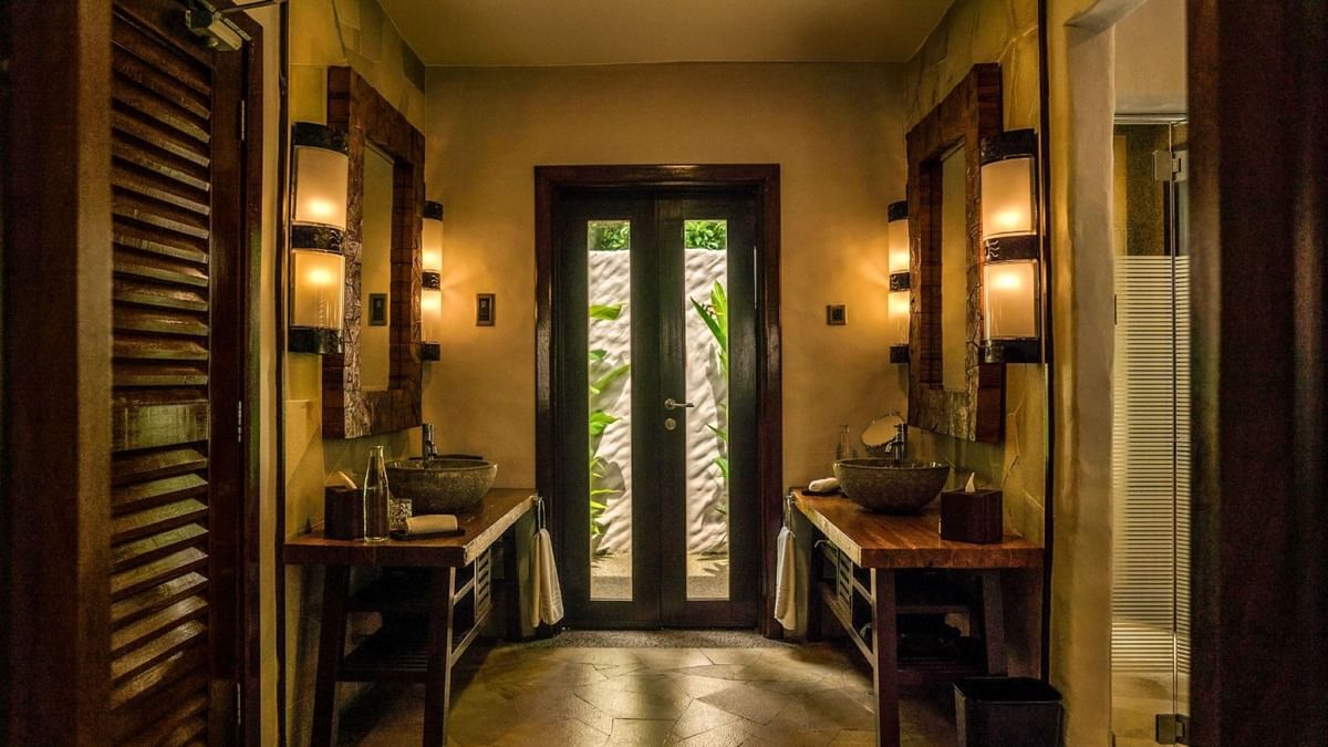 Elegant bathroom with dual stone sinks, wooden vanities, and a glass door in Garden Villa at The Banjaran Hotsprings Retreat