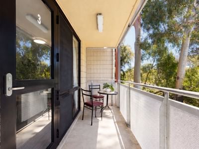 Balcony with table, chairs, and scenic tree view at UniLodge Guild House.