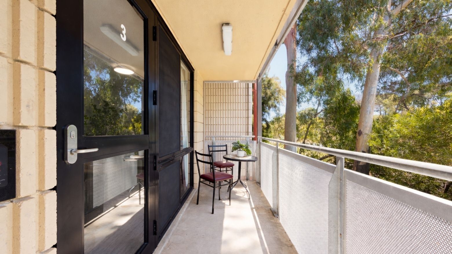 Balcony with table, chairs, and scenic tree view at UniLodge Guild House.