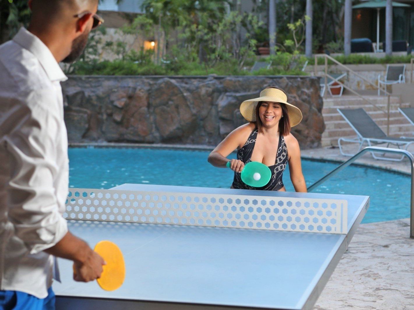 couple playing table tennis near pool