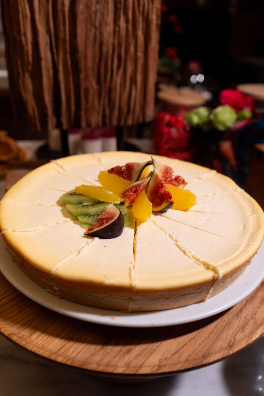 Une part de cheesecake garnie de figues fraîches, de kiwis et d'oranges, posée sur une table au Warwick Paris Champs-Élysées