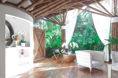 Bright, airy room with bamboo beams, white furniture, and wood floors at Le Cameleon Boutique Hotel