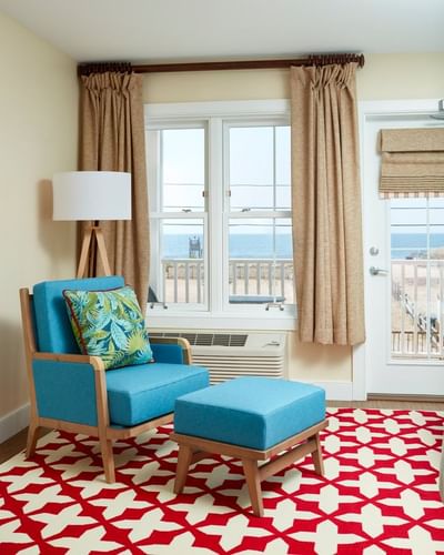 Cozy blue armchair with a tropical pillow and matching footstool in Ocean Queens at The Hotel Maria