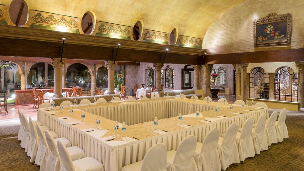 Large square conference table set with white chairs in Salón Los Murales at Quinta Real Aguascalientes