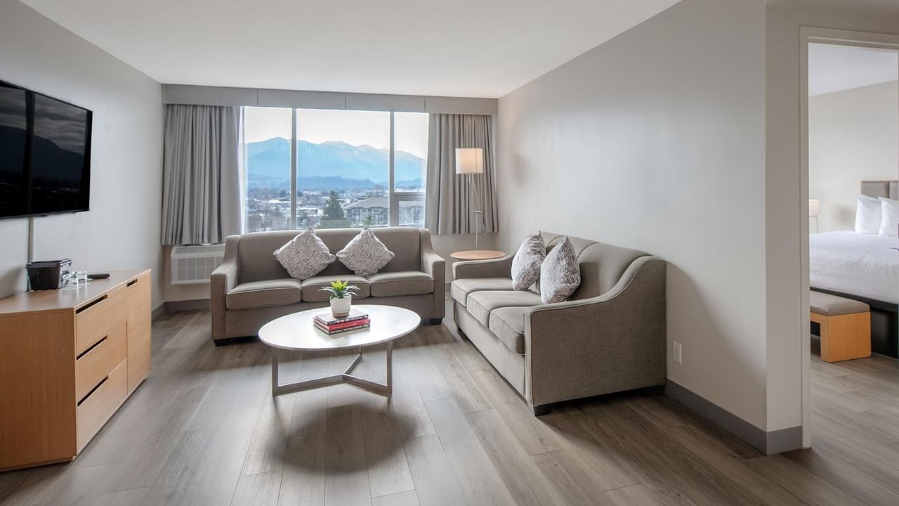 Living area of a hotel suite with couch, coffee table, and view at Coast Chilliwack Hotel by APA.