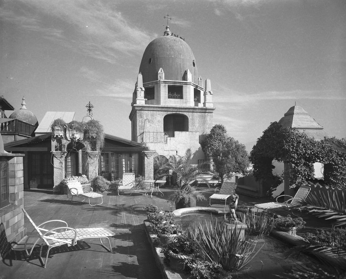 Historic Mission Inn rooftop terrace with lounge chairs, lush planters, and a domed tower