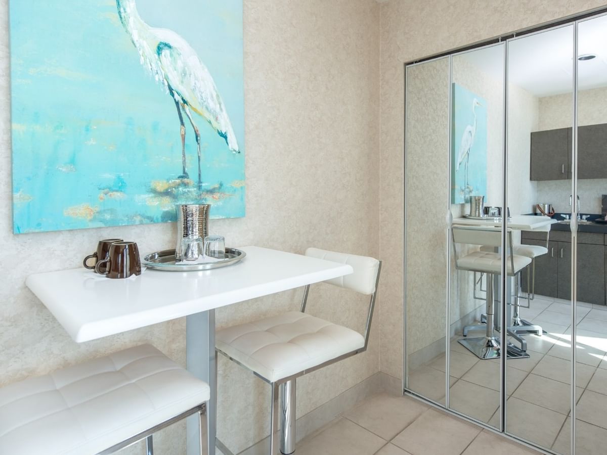 Coast Waterfront Suite with dining table with chairs and a painting of a white bird on wall at Coast Lonsdale Quay Hotel