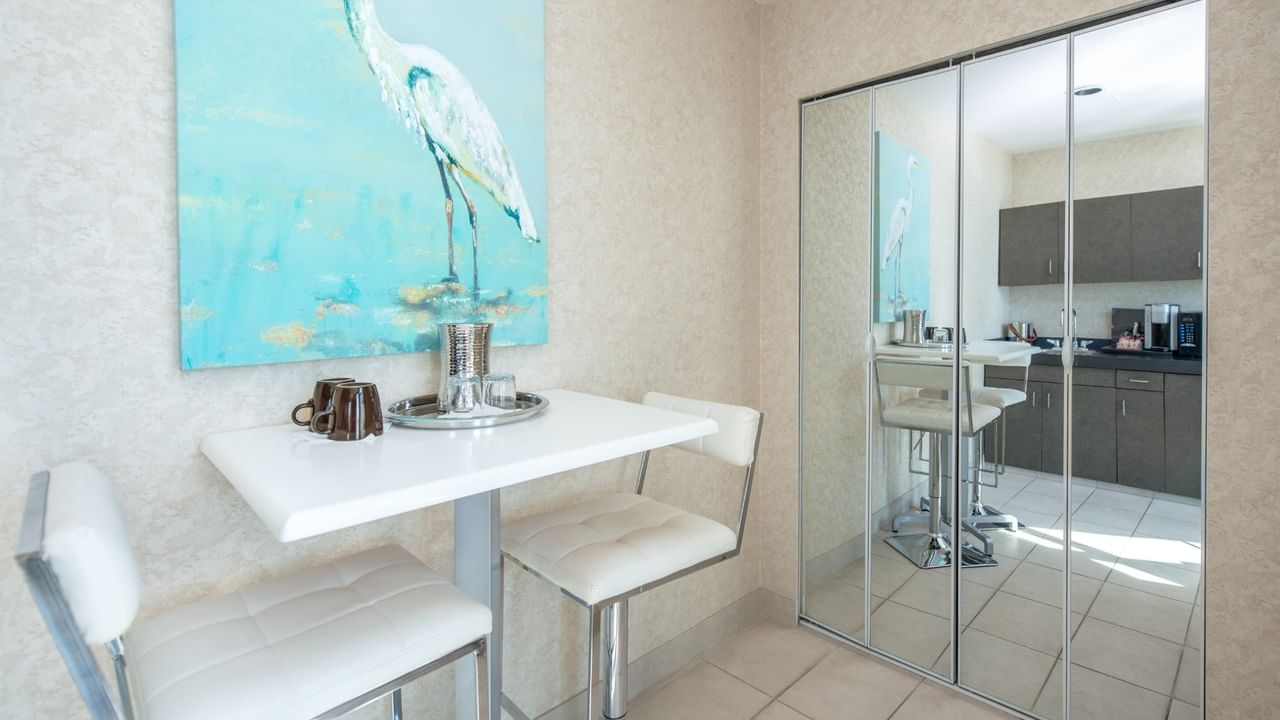 Coast Waterfront Suite with dining table with chairs and a painting of a white bird on wall at Coast Lonsdale Quay Hotel